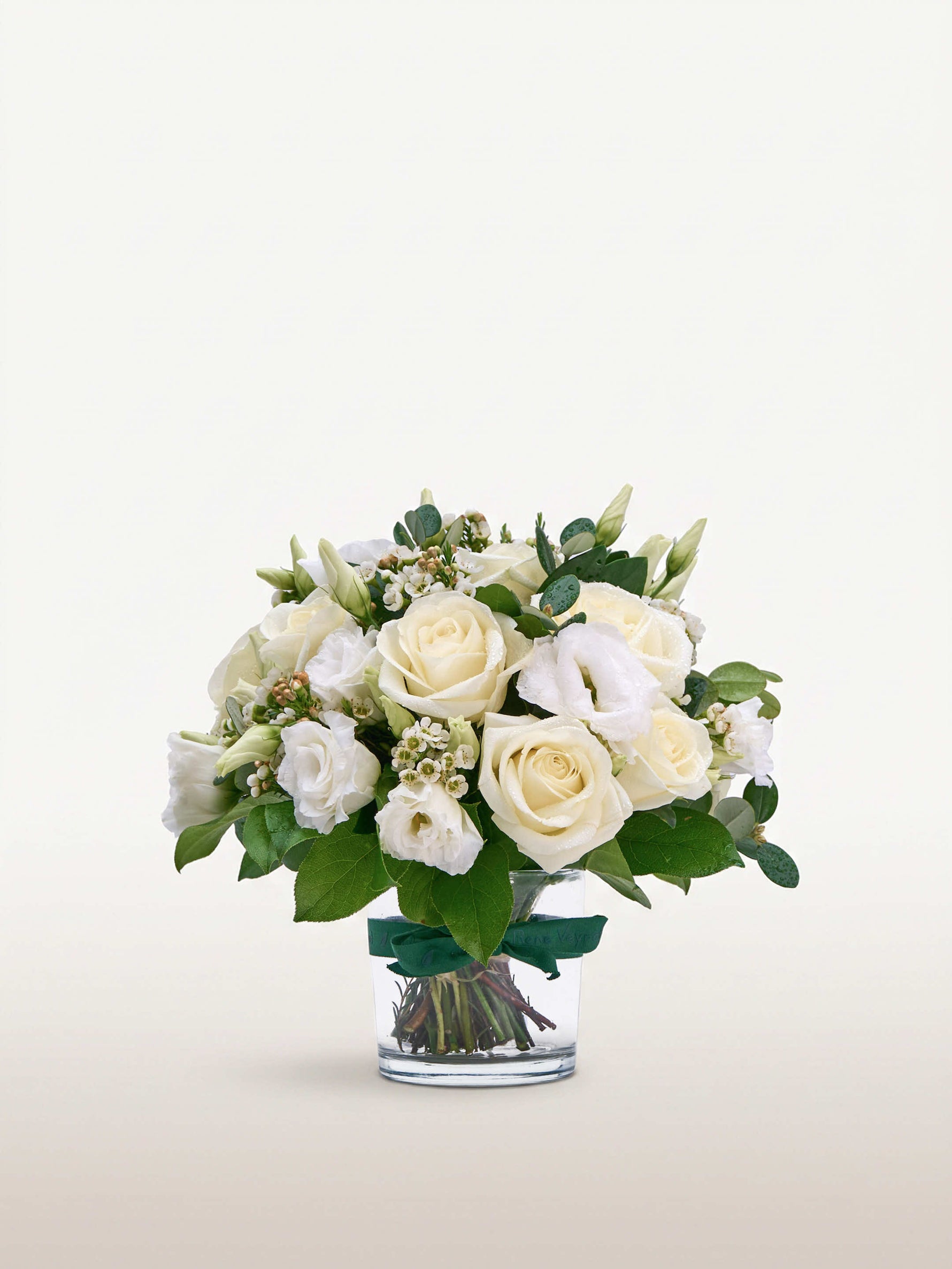 Reine Blanche S, roses blanches et lisianthus dans un vase en verre noué d'un ruban vert