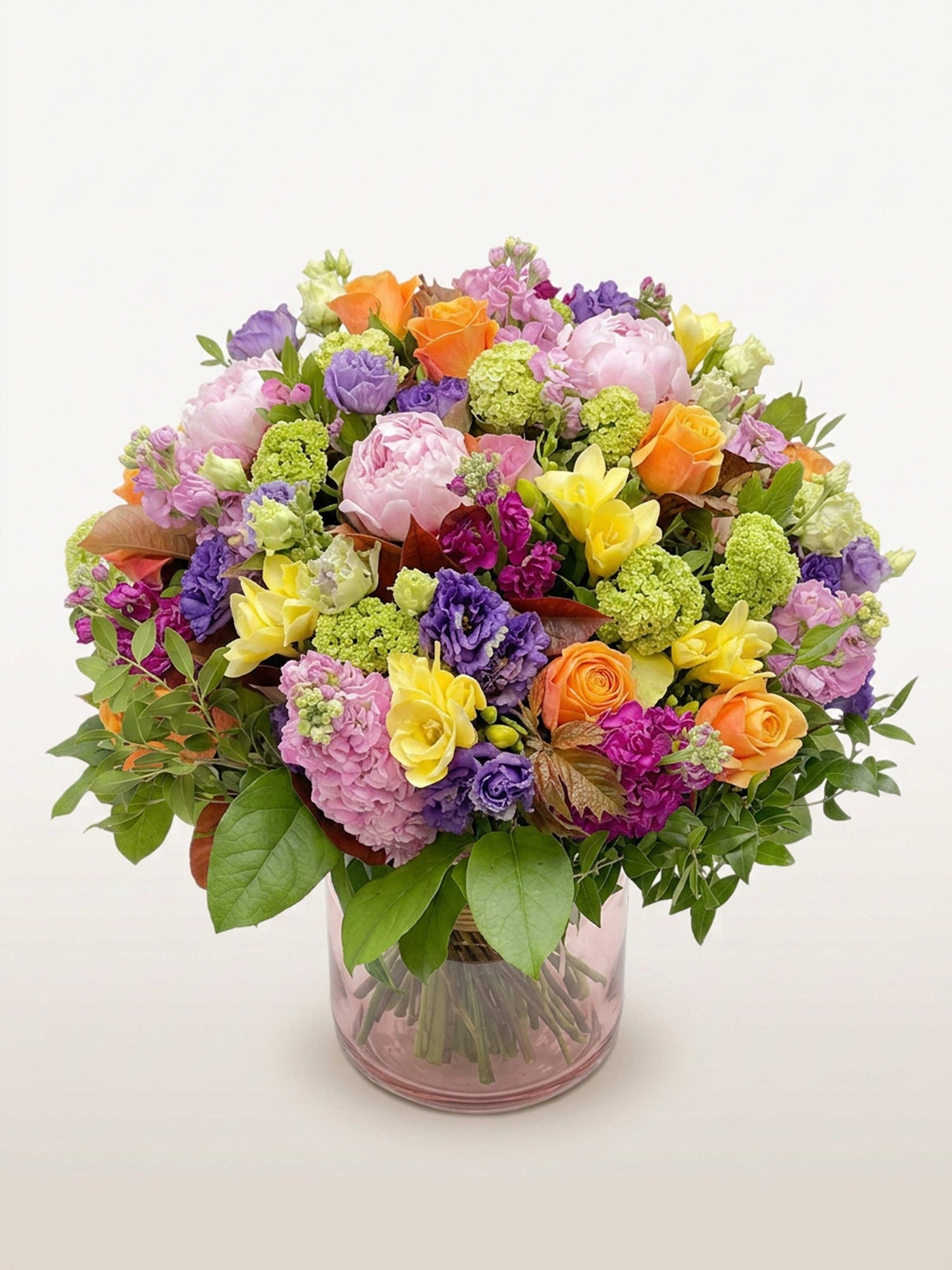 Oiseau de Paradis en bouquet rond XL, mêlant roses, pivoines et freesias multicolores dans un vase en verre