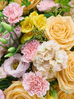 Point du Jour S : roses pêche, œillets roses, freesias jaunes et lisianthus rosés serrés entre eux