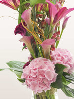 Arums roses et fuchsia, hortensias roses et célosies pourpres autour de tiges entrelacées