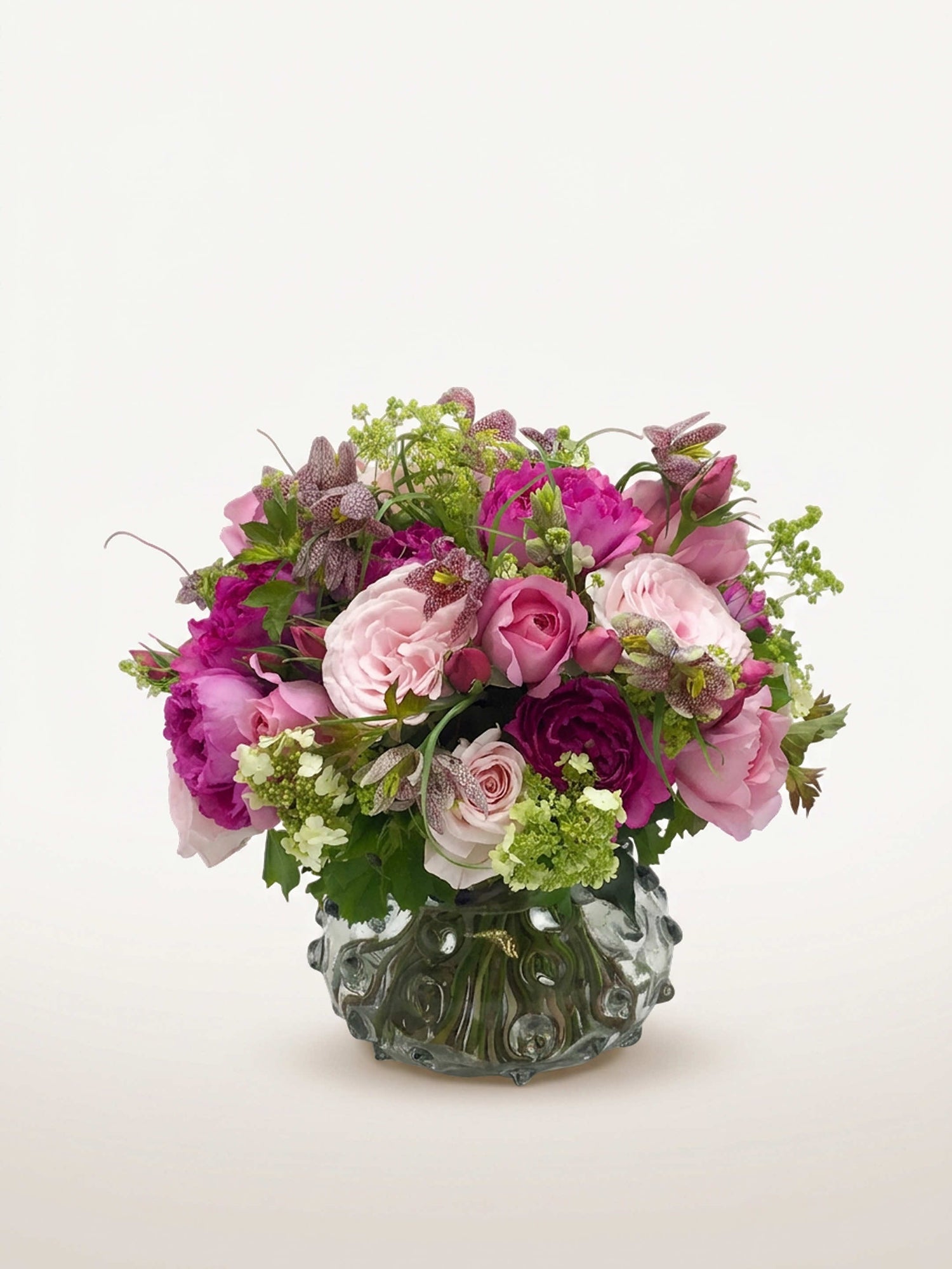 Parc Monceau, roses roses et pivoines fuchsia, fritillaires mouchetées et viornes vertes dans un vase gris texturé