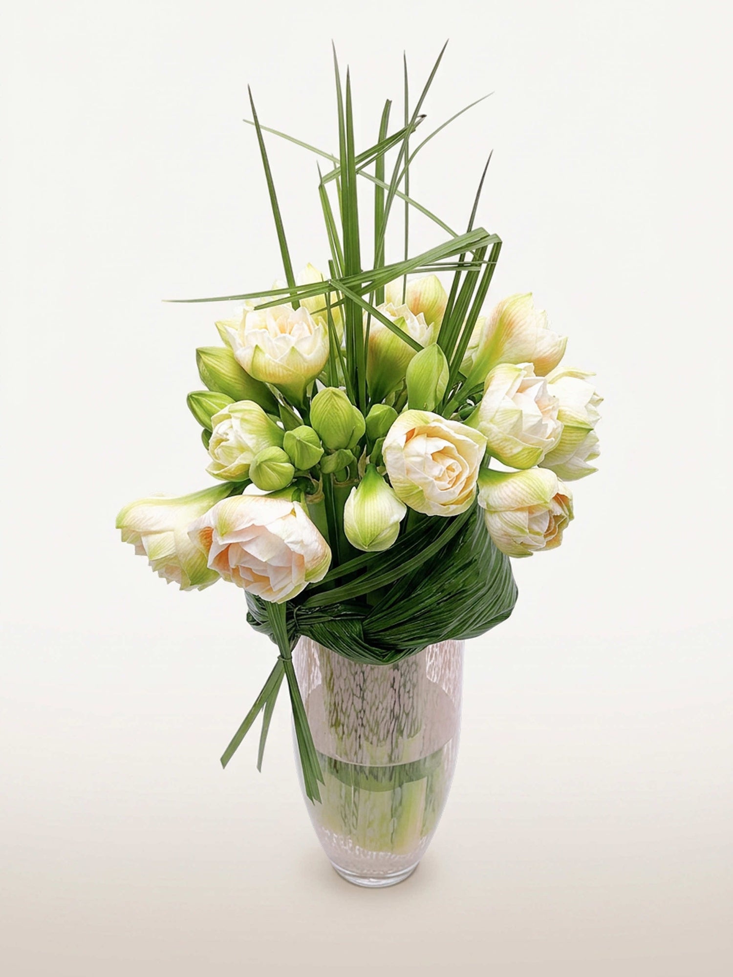 Villa des Nymphéas grand format présente un bouquet graphique d'amarylis ivoire et vertes avec de longues herbes dans un vase en verre