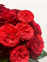 Roses Cornaline rouges aux pétales denses et enroulés, associées à des roses classiques et du feuillage vert