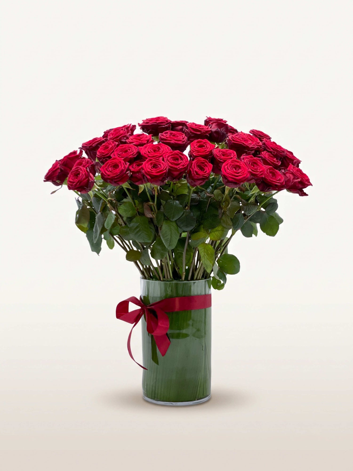 Royal N°75 dévoile une brassée XL de roses rouge velouté dans un vase cylindrique noué d'un ruban carmin